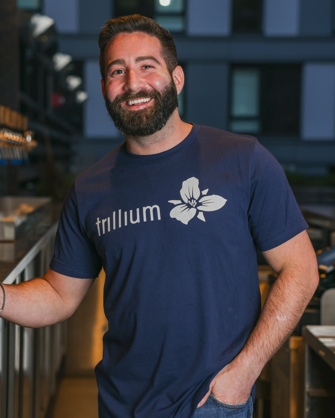 Male wearing navy blue Trillium classic logo t-shirt and white Trillium flower