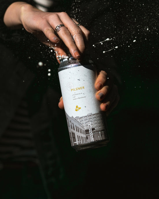 Can of pilsner being cracked open with beer spraying
